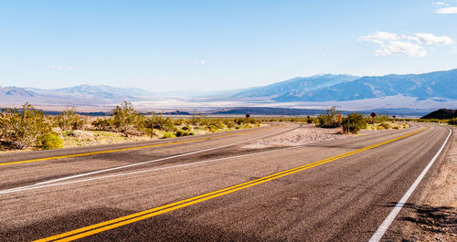 Road leading towards mountains against sky