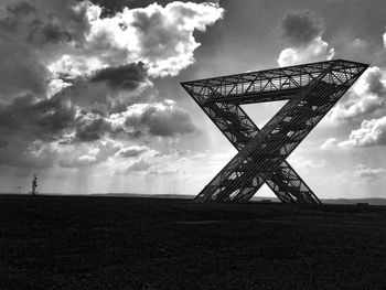 Low angle view of metallic structure on field against sky