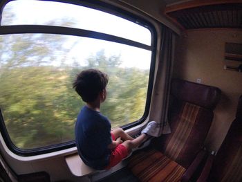 Rear view of boy sitting in bus