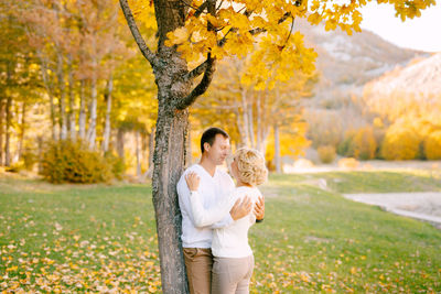 Happy young woman standing by plants during autumn