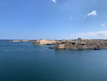 Buildings by sea against blue sky