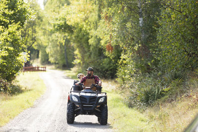 Male farmer with dog driving four-wheeler
