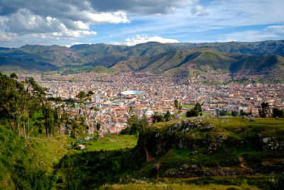 Aerial view of townscape and mountains against sky