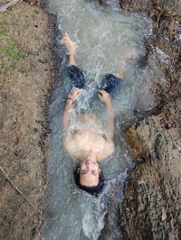High angle view of shirtless man lying in stream