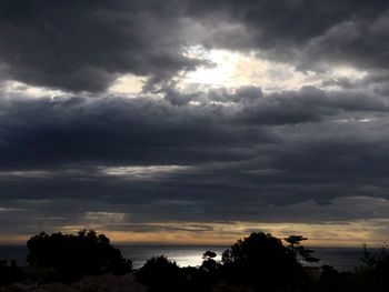 Silhouette of trees against cloudy sky