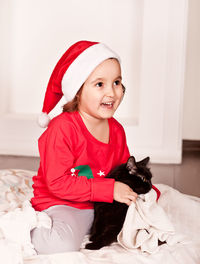 Portrait of cute baby girl sitting on bed at home