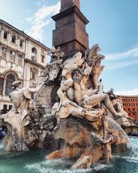 Statue by fountain against sky