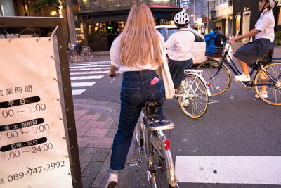 Rear view of people riding bicycle on road