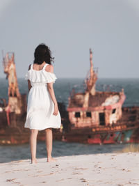 Rear view of woman standing against sea in city