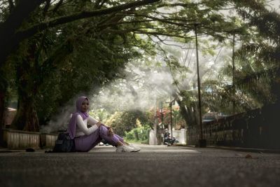 Man sitting on road amidst trees