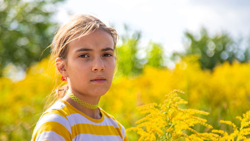 Close-up of cute girl standing amidst yellow flowers