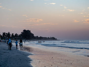 People on beach against sky during sunset