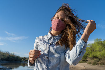 Midsection of woman holding umbrella against blue sky