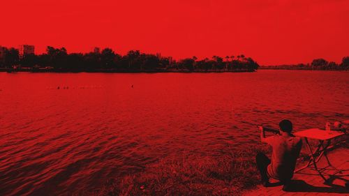 Silhouette people standing at lakeshore against scenic view of lake