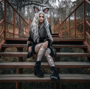 Full length of young woman sitting on steps outdoors