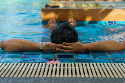 Back view of a tanned colour man relaxing in the swimming pool. summer vacation