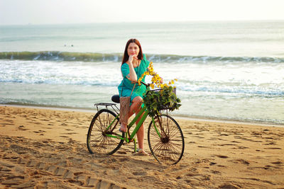 Full length of woman sanding by bicycle on beach