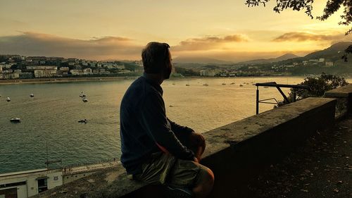 Man looking at sea against sky during sunset