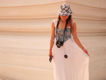Young woman standing against wall
