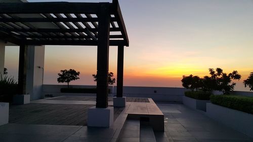 Gazebo on building terrace against sky during sunset