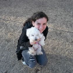 High angle portrait of young woman holding puppy on field