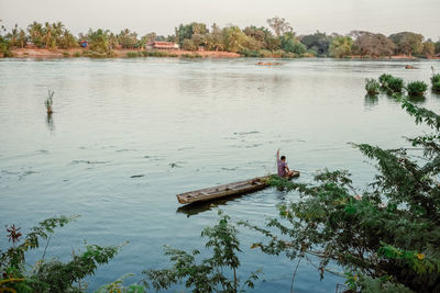 Rear view of fisherman fishing in boat at lake