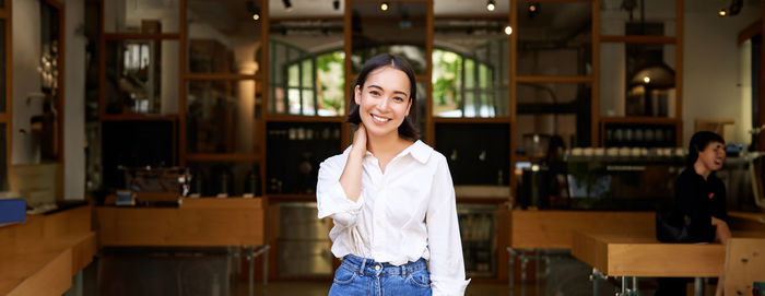 Portrait of young woman standing in library