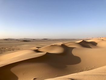 Sand dunes in desert against clear sky