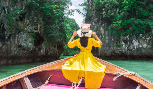 Rear view of woman in boat against trees