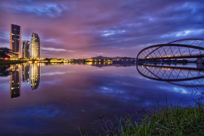 Reflection of illuminated bridge in lake at sunset
