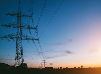 Low angle view of silhouette electricity pylon against sky during sunset