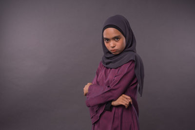 Portrait of young woman standing against purple background