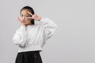 Girl looking away while standing against white background