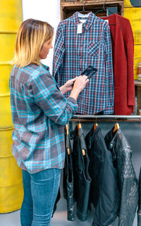 Blonde woman using digital tablet while checking stock on vintage clothes shop