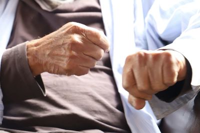 Midsection of senior man fist bumping with doctor in hospital