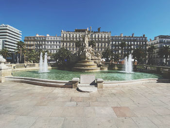 Fountain in city against clear sky