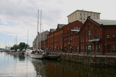 Boats moored in river with buildings in background