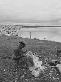 Man sitting on land against sky