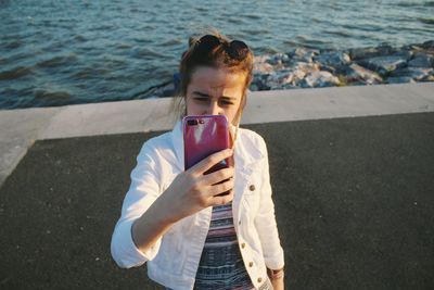 Young woman taking selfie from mobile phone against sea