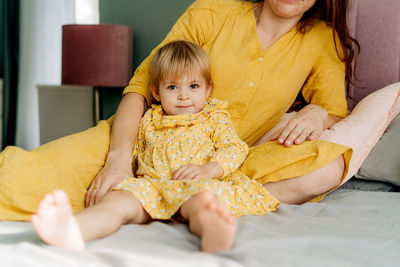 Portrait of cute girl playing with teddy bear on bed at home