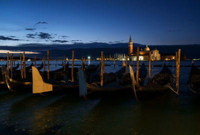 Gondolas moored in grand canal against st mark square during night