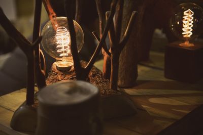 Close-up of lit light bulb on table