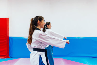 Side view of women practicing karate at gym