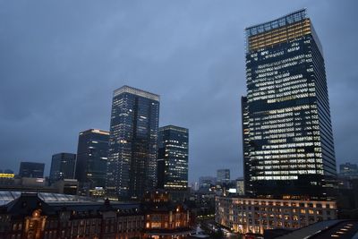 Illuminated buildings in city against sky at dusk