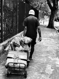 Rear view of man walking on sidewalk in city