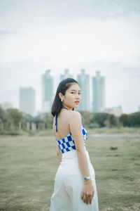 Portrait of young woman standing against sky