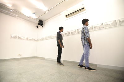 Young man looking away while standing on wall