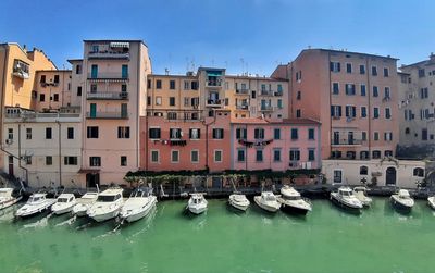 Boats moored in canal by buildings in city