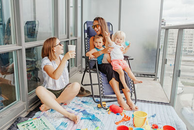 Young mothers spending time together with children babies on balcony at home. staycation 