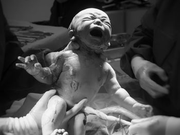 Close-up of hands holding newborn baby in hospital